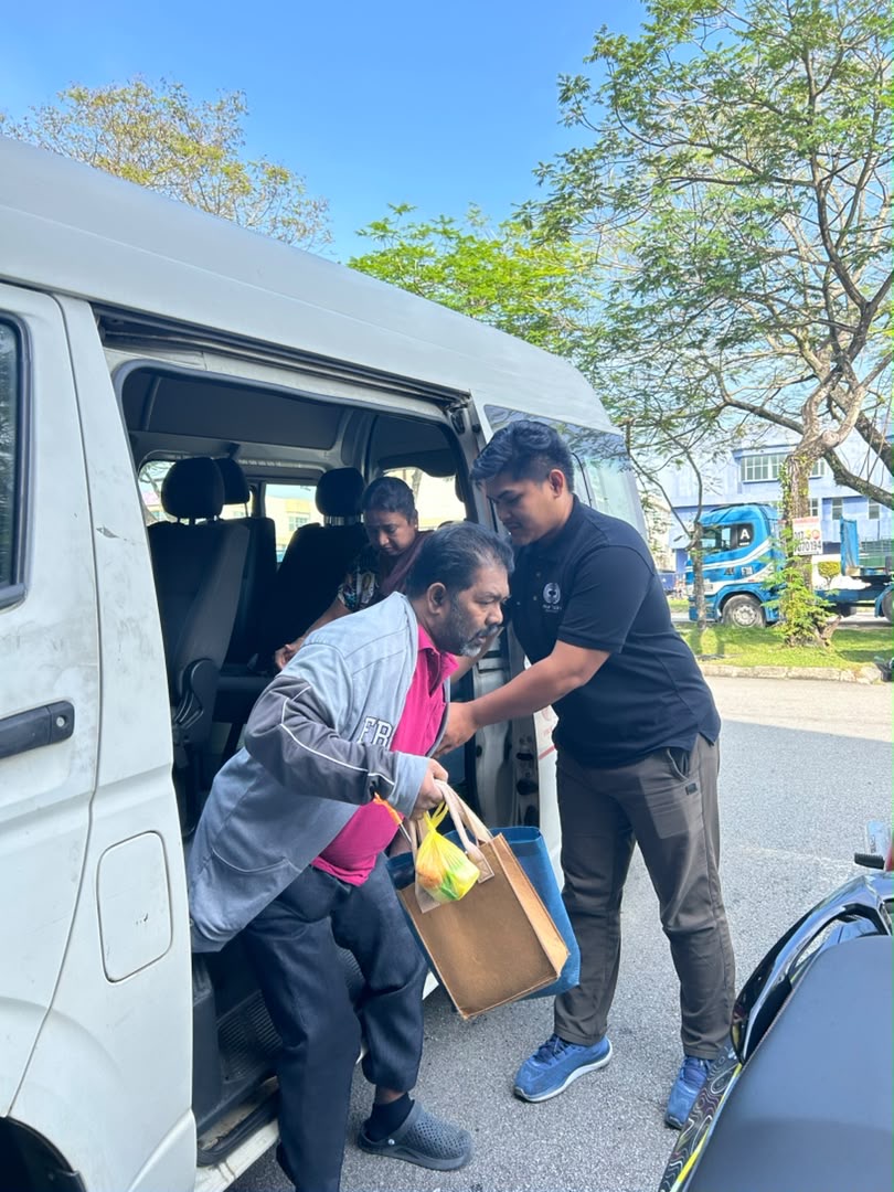 Driver helping a patient alight safely for patient transport at Pusat Hemodialisis Nur Ain
