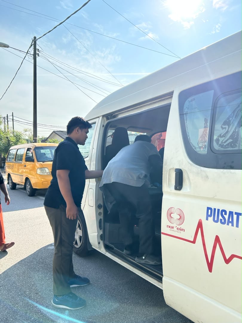 Driver assisting patient into patient transport at Pusat Hemodialisis Nur Ain